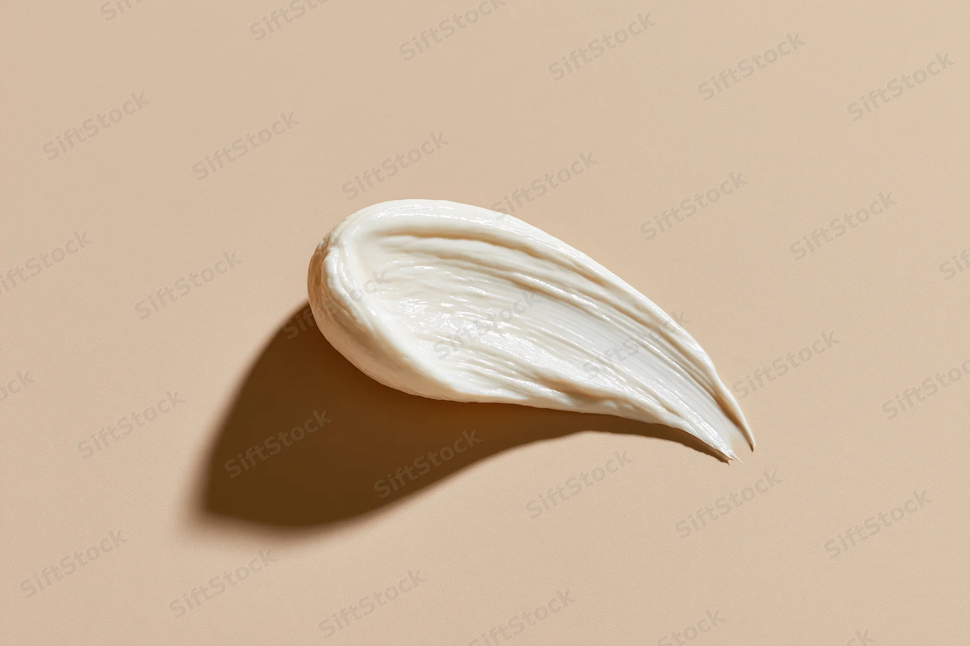 Smooth smear of white face cream on beige background