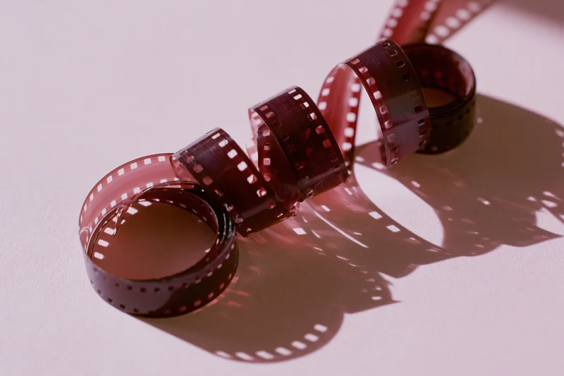Curled 35mm film negative strip forming spirals on a white surface with shadows