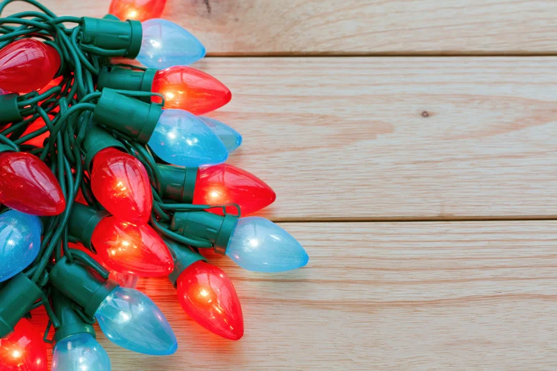 Tangled cluster of red and blue christmas lights on wooden surface with copyspace