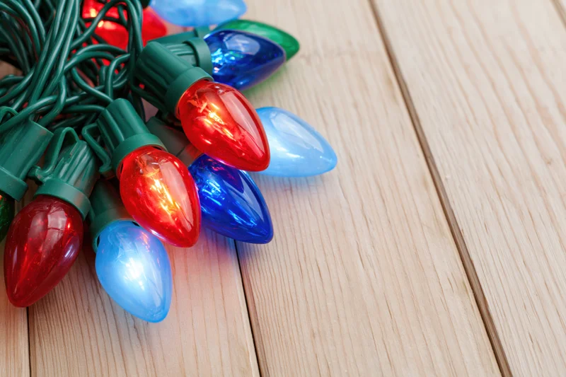 Tangled cluster of colorful christmas lights resting on wooden surface