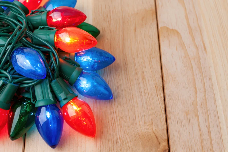 Colorful christmas lights tangled on wooden surface with copyspace