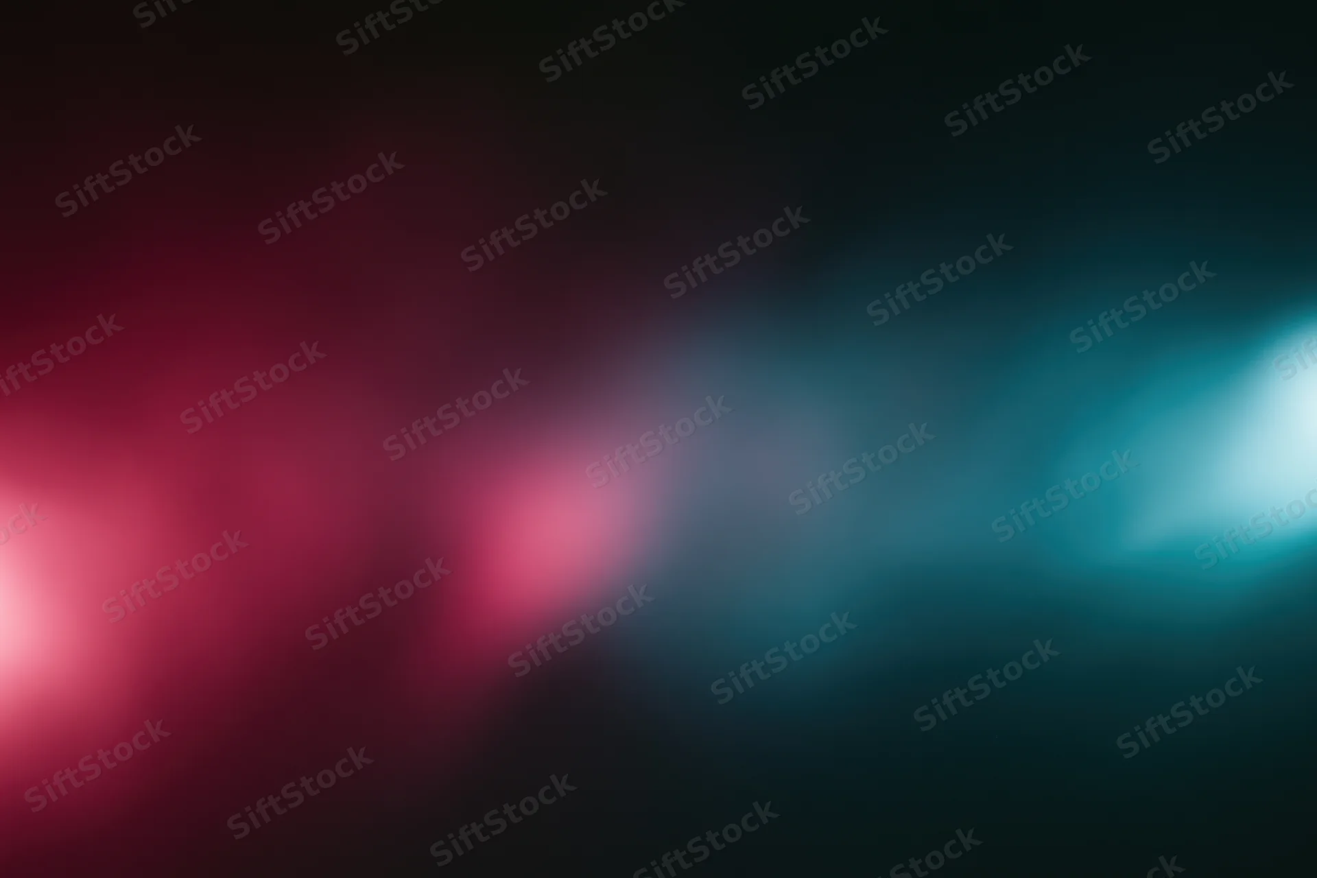 Abstract blurred light gradient transitioning from deep red to teal on dark background