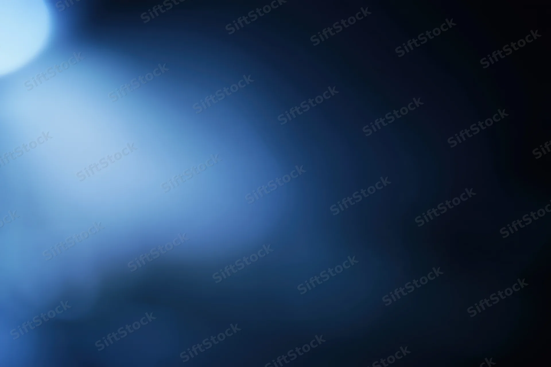 Abstract defocused background with soft glowing light source in blue and dark tones