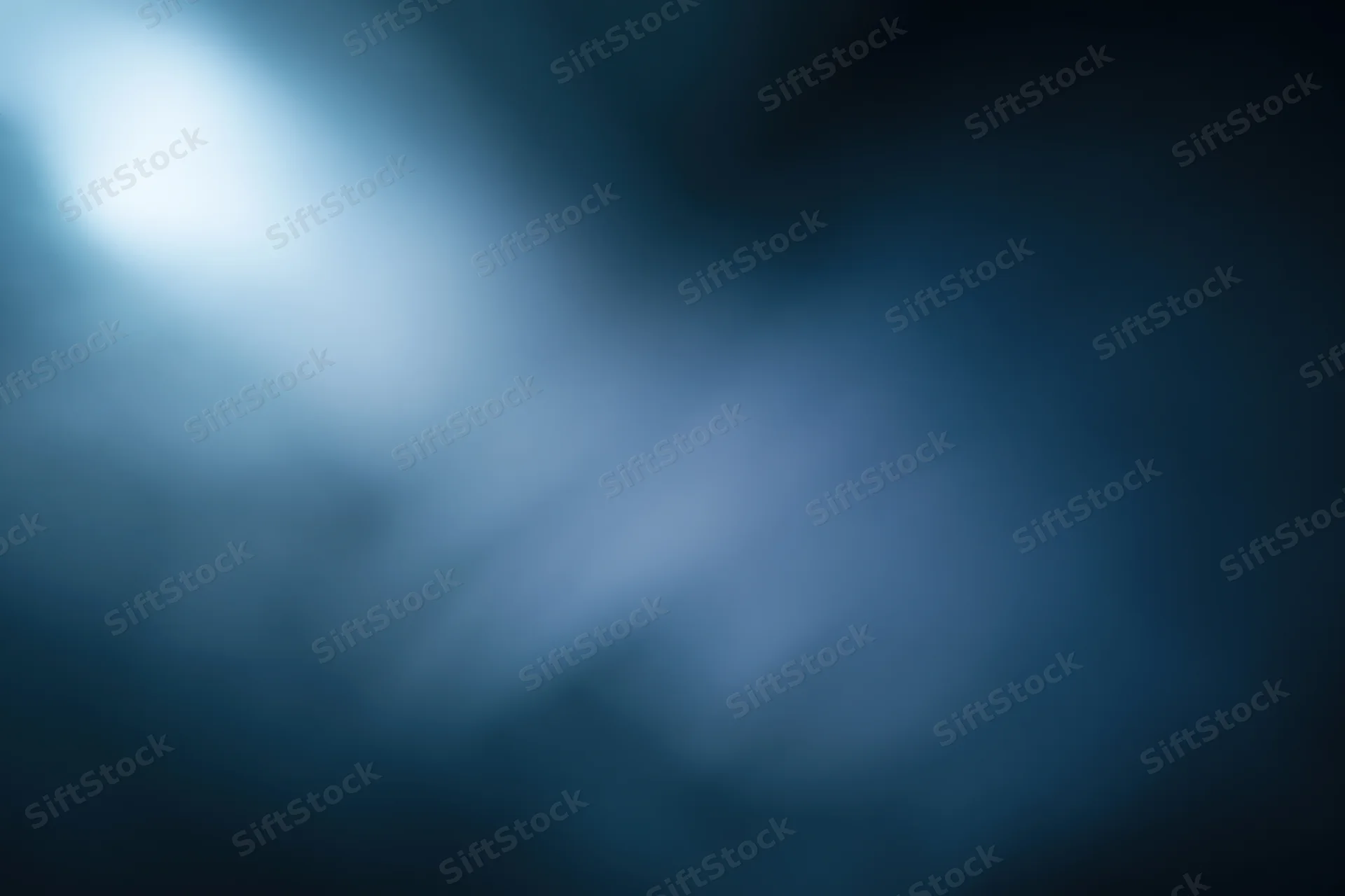 Abstract defocused background with soft glowing light source in blue and dark tones