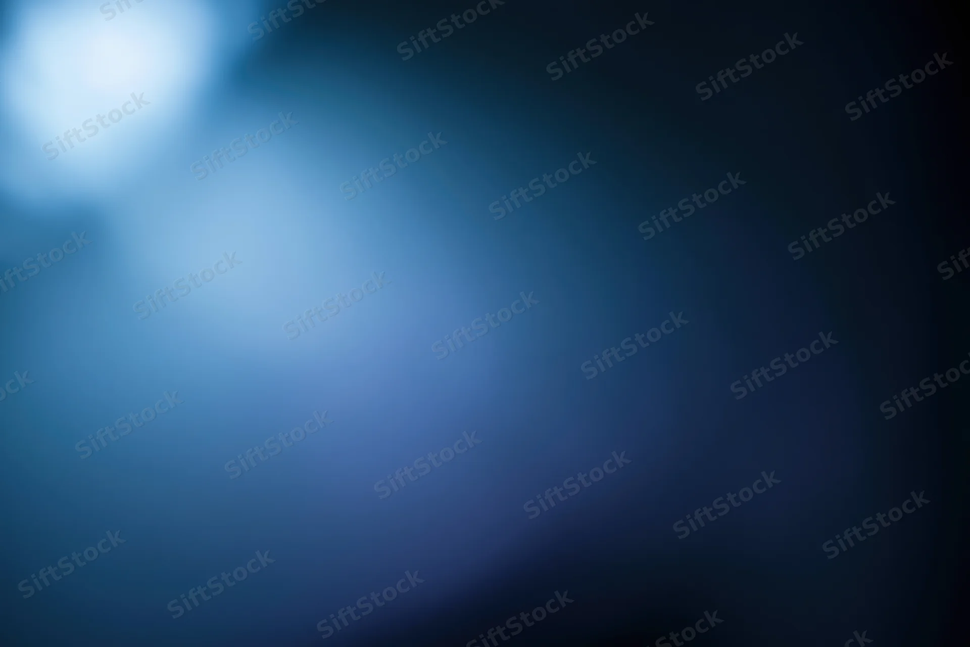 Abstract defocused background with soft glowing light source in blue tones