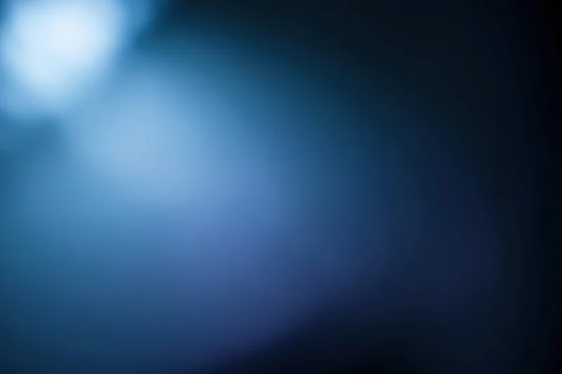 Abstract defocused background with soft glowing light source in blue tones