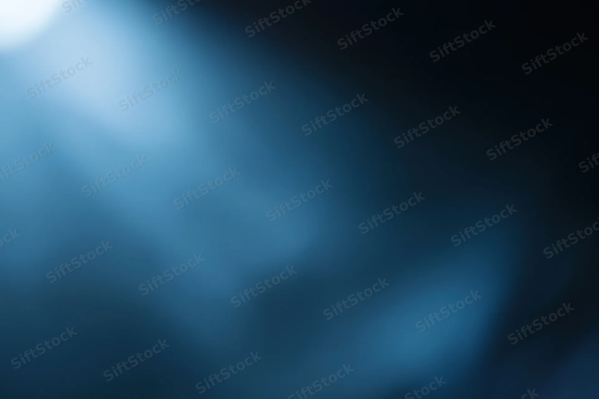 Abstract defocused background with soft glowing light source in blue and dark tones