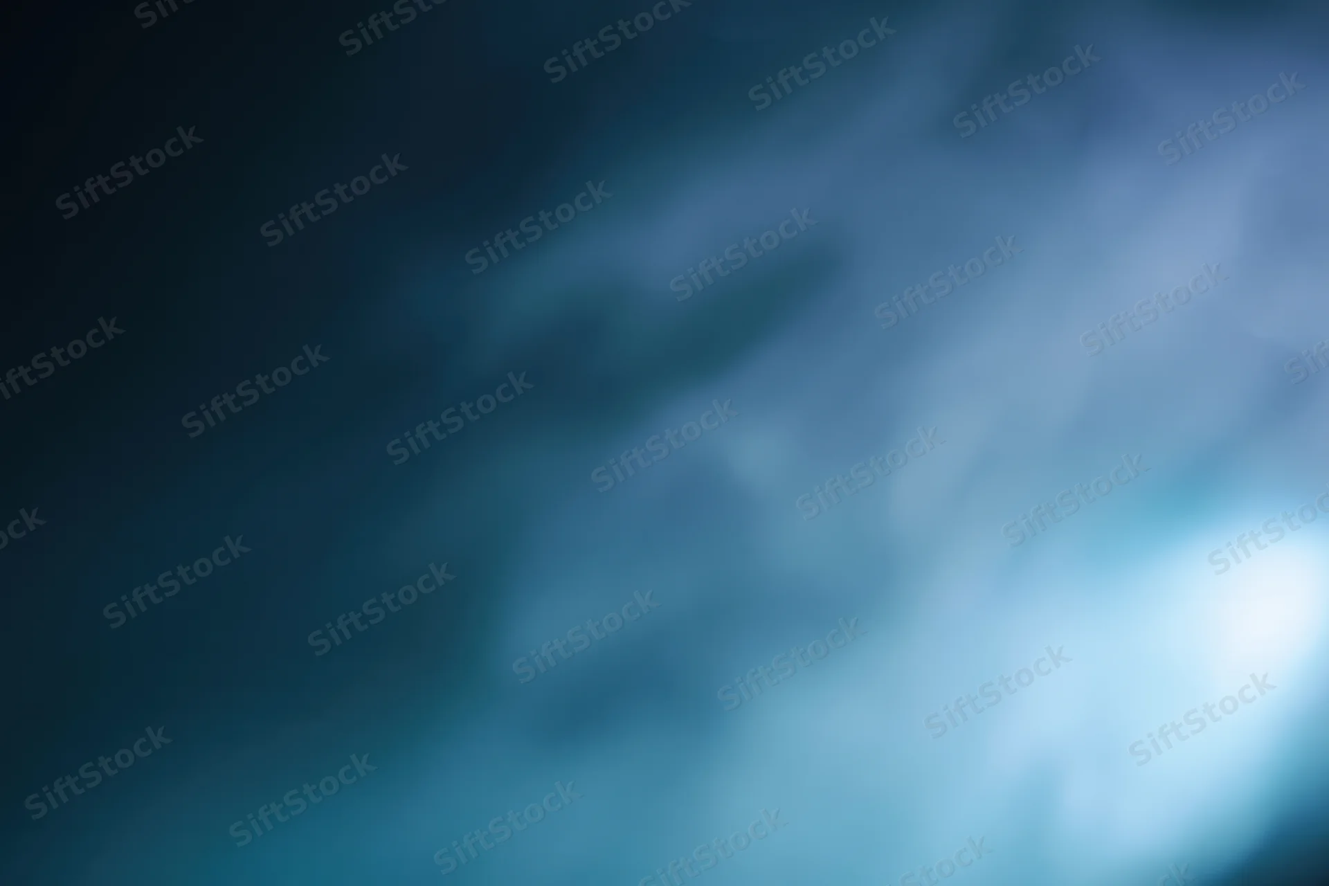 Abstract defocused background with soft glowing light source in blue and teal tones