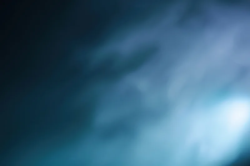 Abstract defocused background with soft glowing light source in blue and teal tones