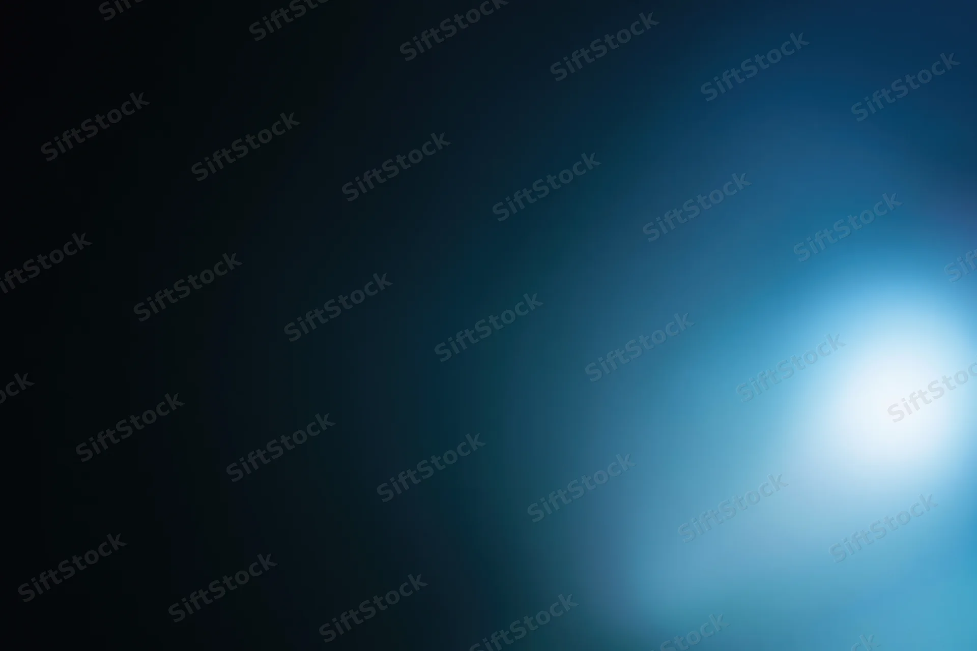 Abstract defocused background with soft glowing light source in blue and dark tones