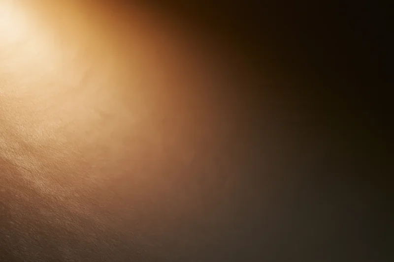 Warm spotlight glowing softly on a smooth textured surface with gradient background
