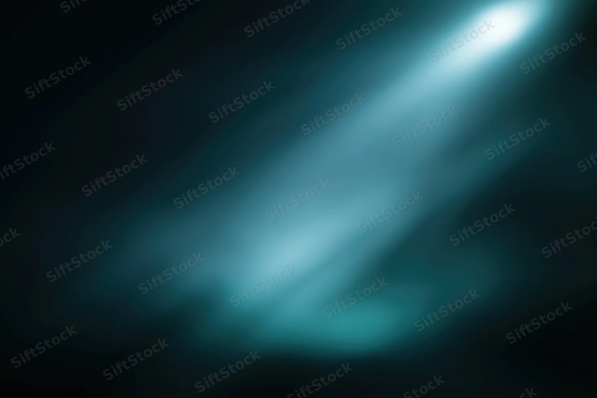 Soft blue spotlight beam glowing in dark smoky atmosphere with smooth gradient background