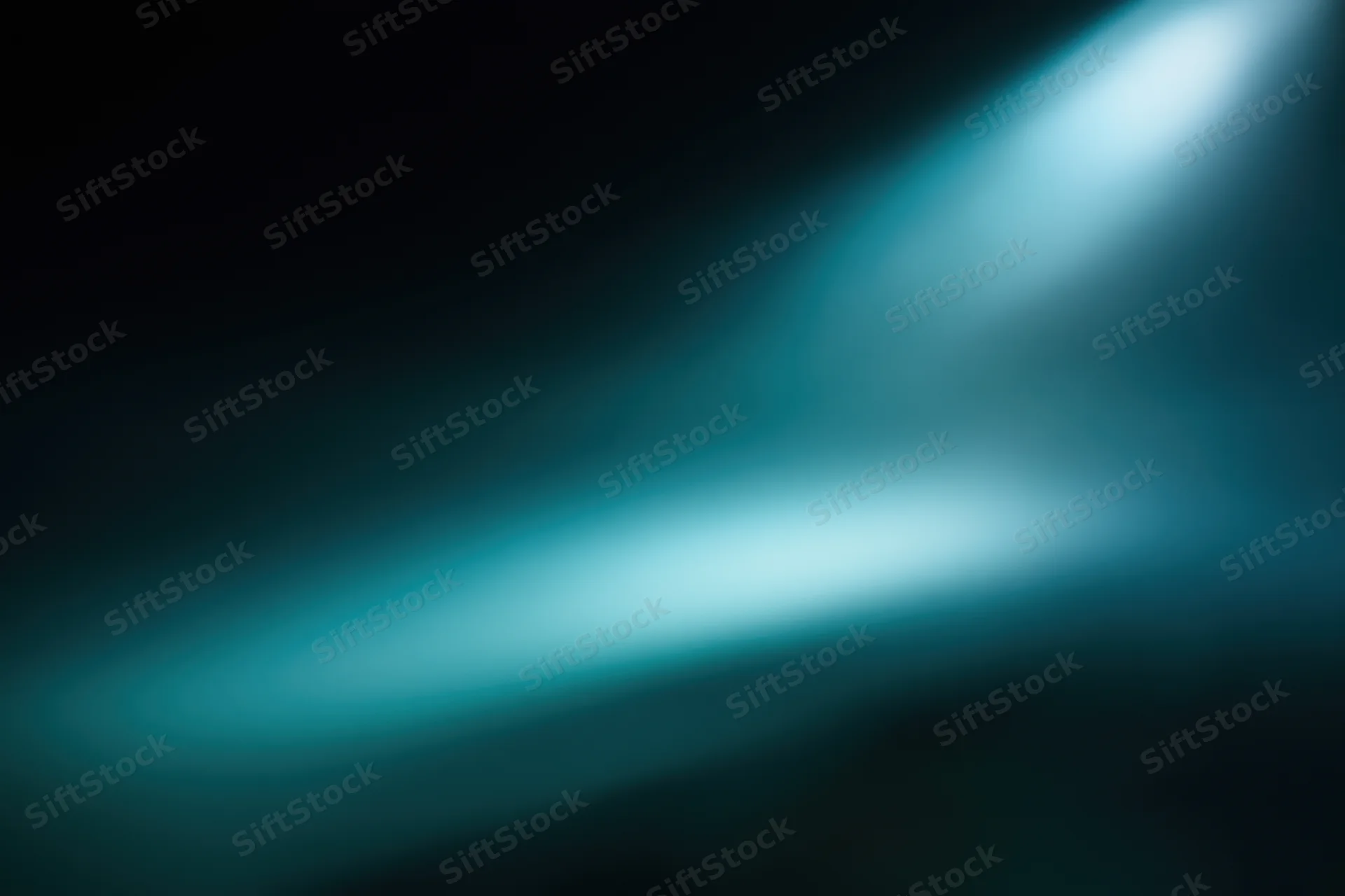 A spotlight beam glowing in a dark abstract background with soft blue gradient