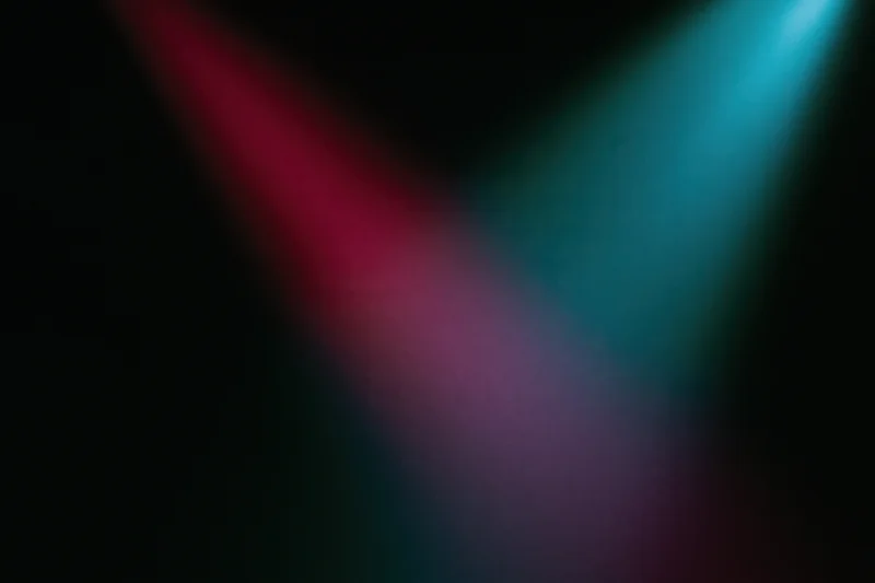 Two overlapping beams of red and blue stage lighting on a dark wall