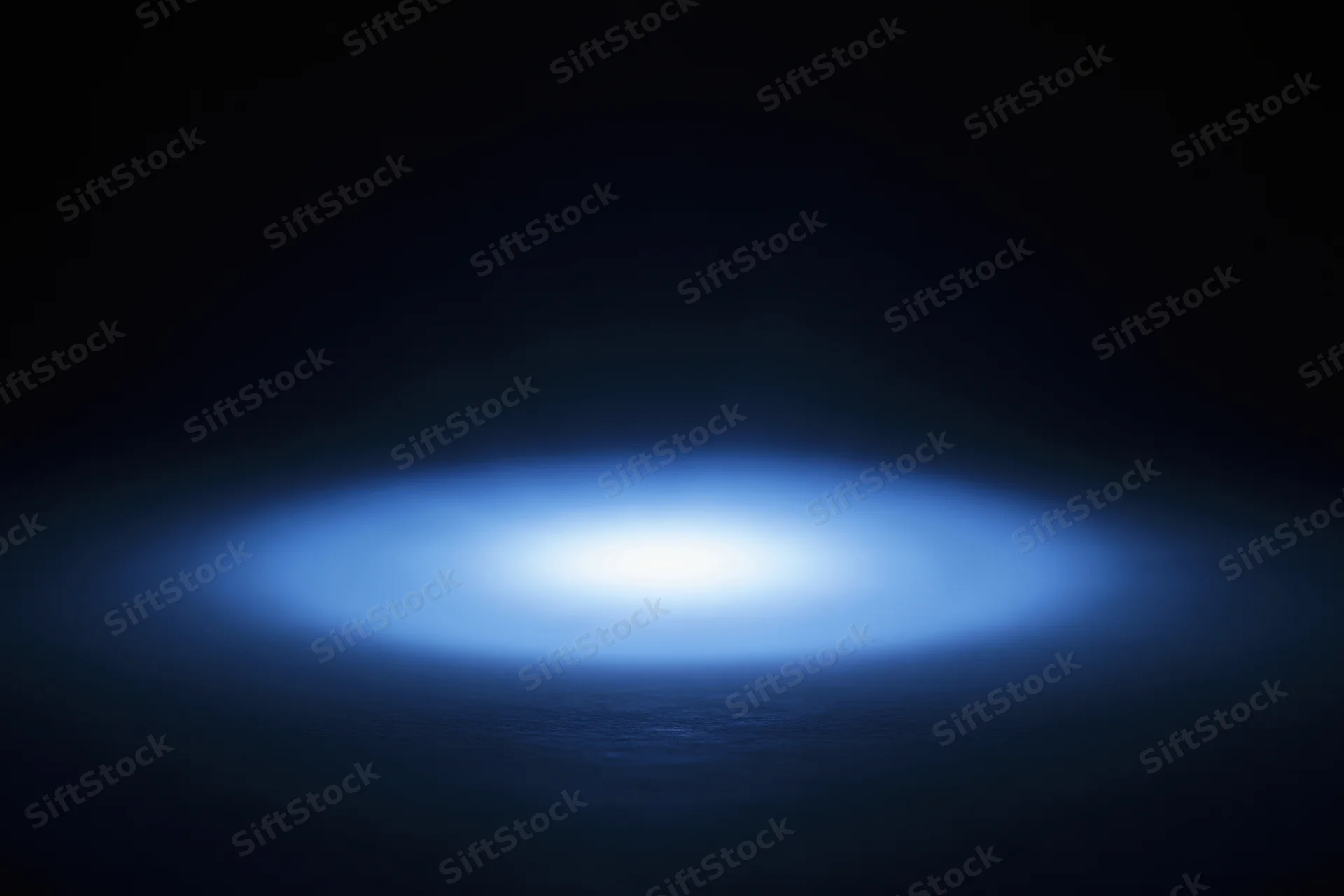 Soft blue radial light glow centered on dark studio backdrop