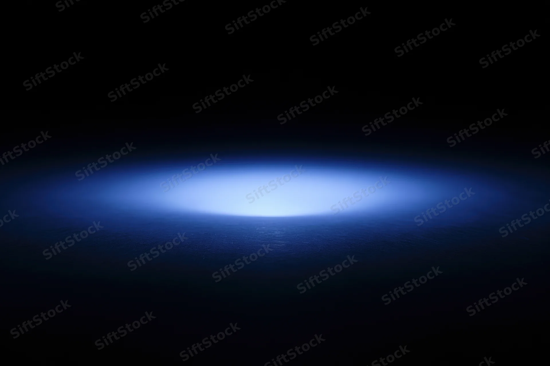 Soft blue radial light glow on dark studio backdrop with central focus and copyspace