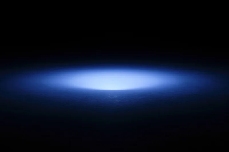 Soft blue radial light glow on dark studio backdrop with central focus and copyspace
