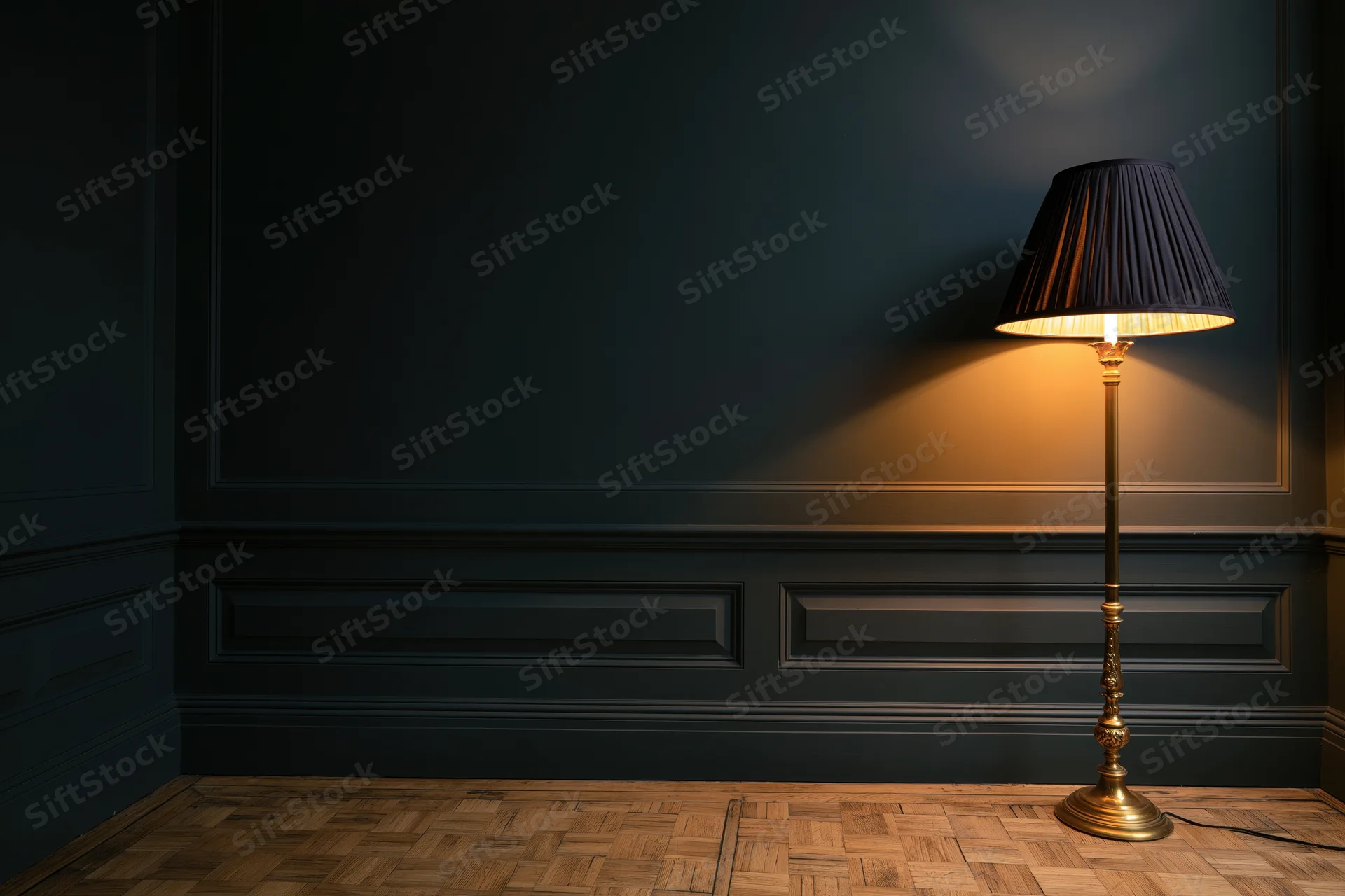 Ornate brass floor lamp with dark pleated shade glowing in a dimly lit room with dark paneling and parquet flooring