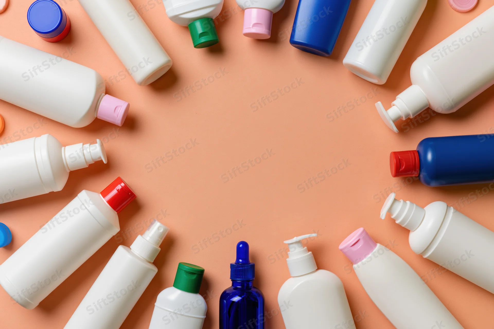 Personal care product bottles arranged in a circle on peach background with central copyspace