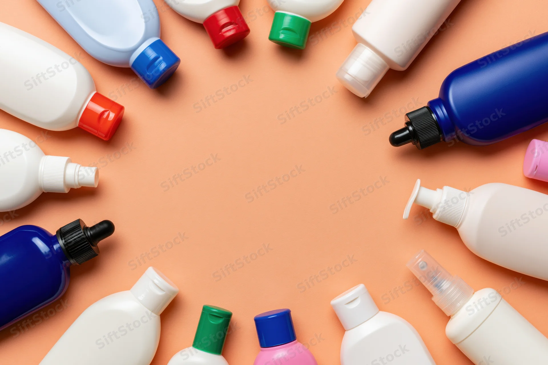 Personal care product bottles and dispensers arranged in a circle on peach background with central copyspace