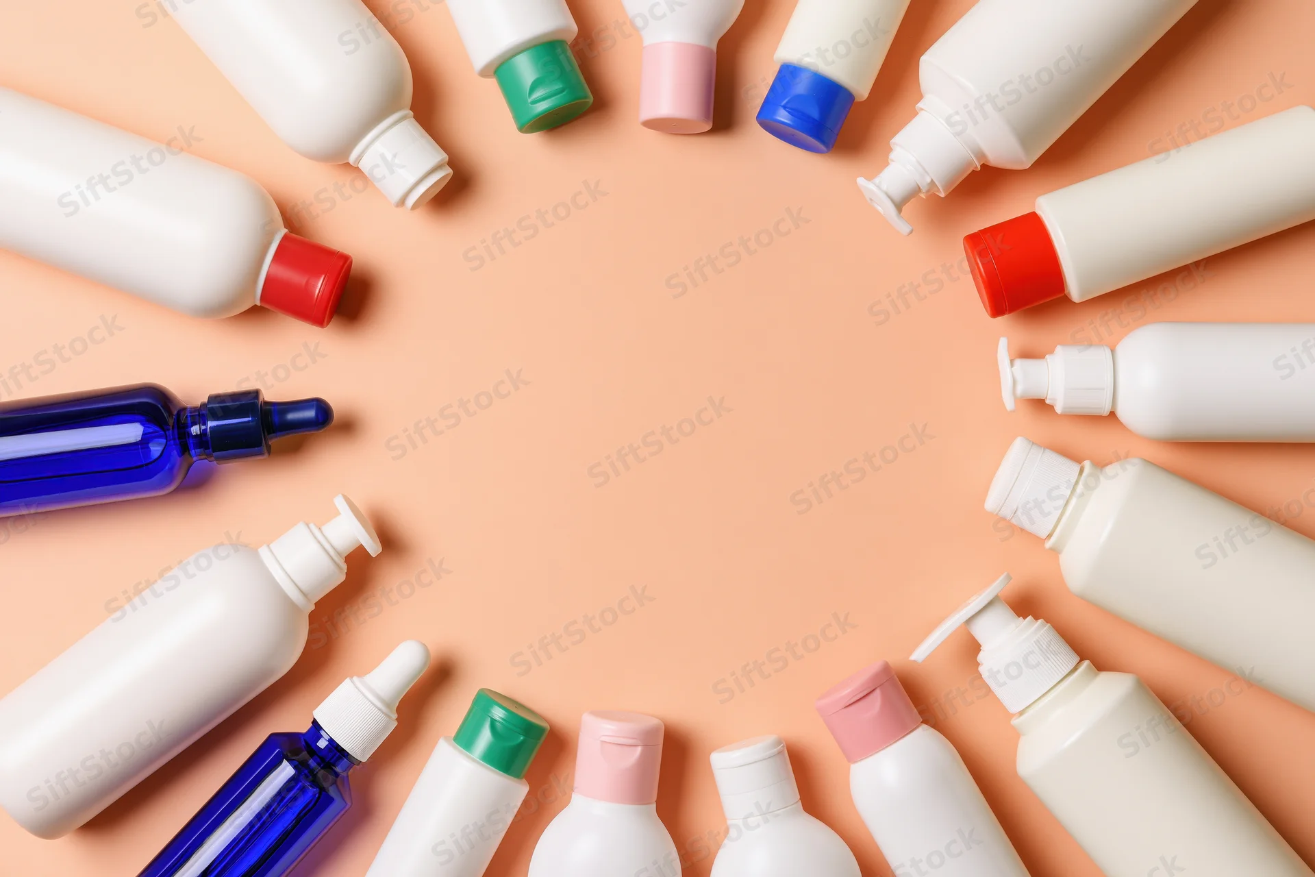 Assorted personal care bottles and dispensers arranged in a circle on peach background with central copyspace
