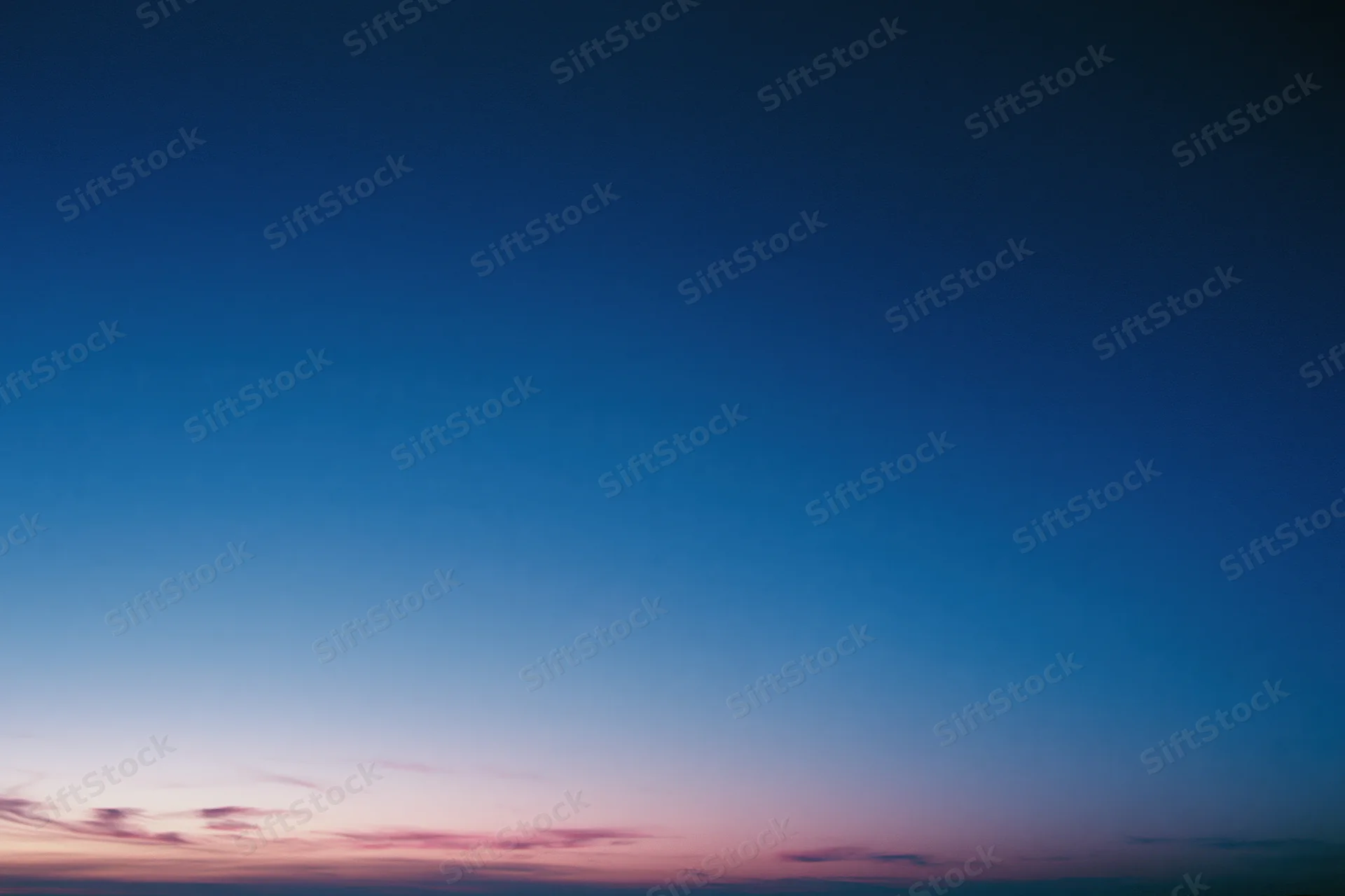 Twilight sky with soft pink and purple clouds fading into deep blue above the horizon
