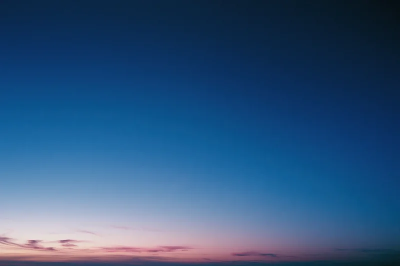 Twilight sky with soft pink and purple clouds fading into deep blue above the horizon
