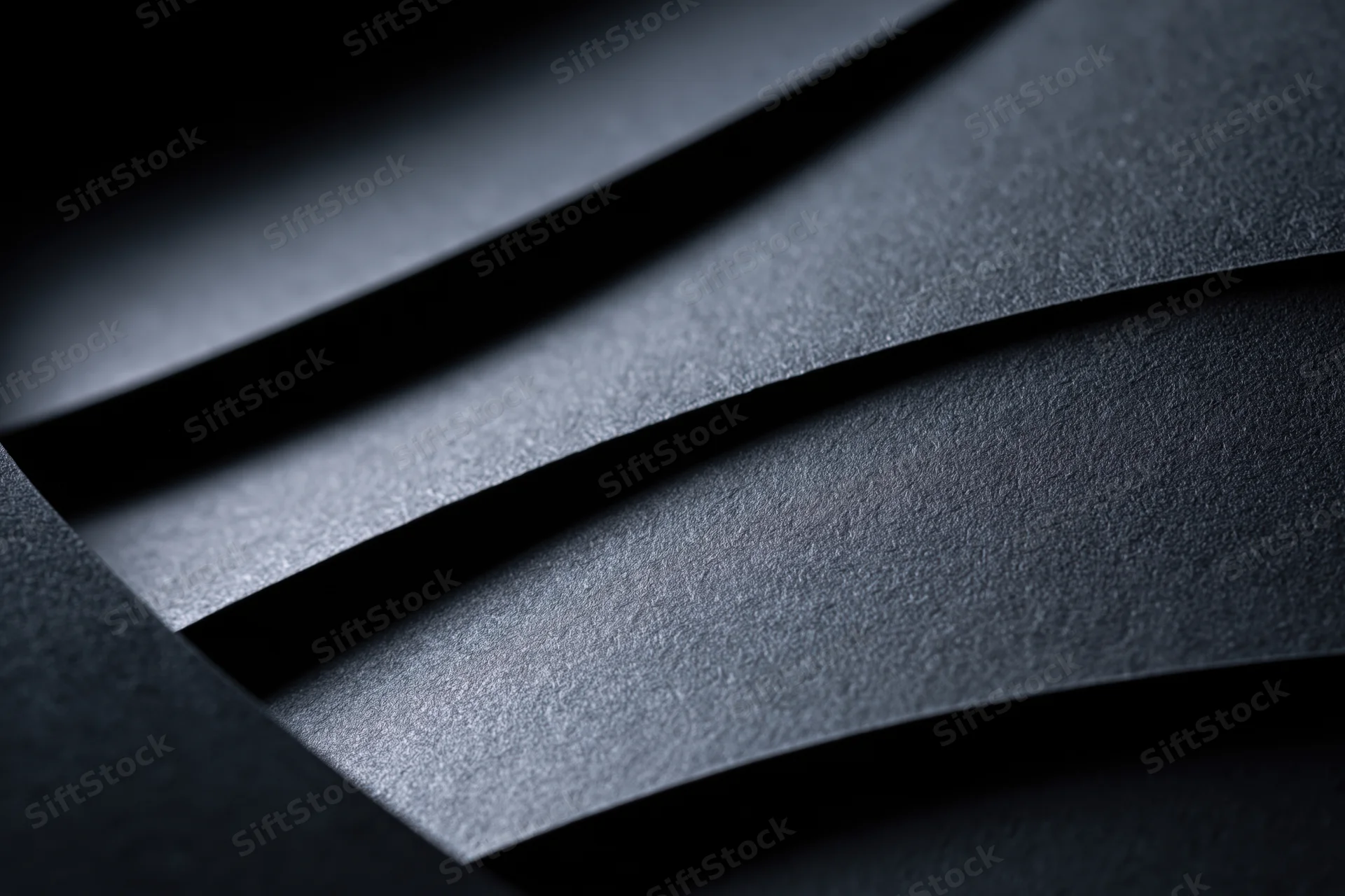 Layered black cardstock sheets arranged in curved abstract pattern with soft shadows and matte texture