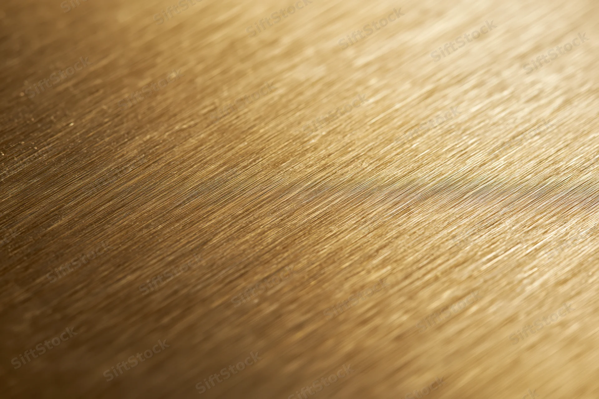 Close-up of brushed gold metal surface with linear texture and warm reflective sheen