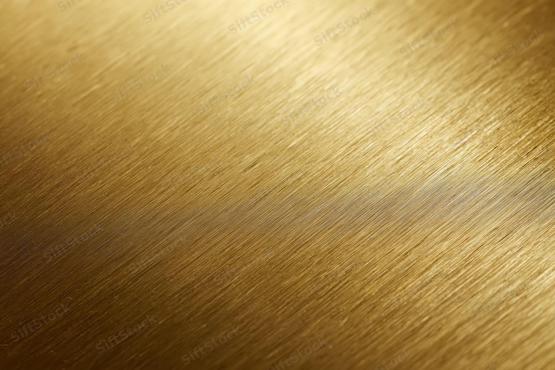Close-up of brushed gold metal surface with linear texture and warm gradient lighting