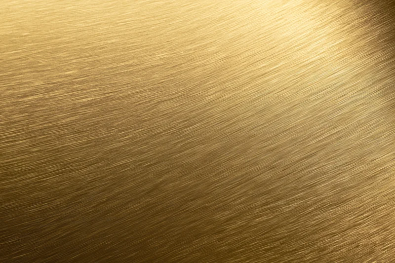 Close-up of brushed gold metal surface with diagonal texture and light gradient