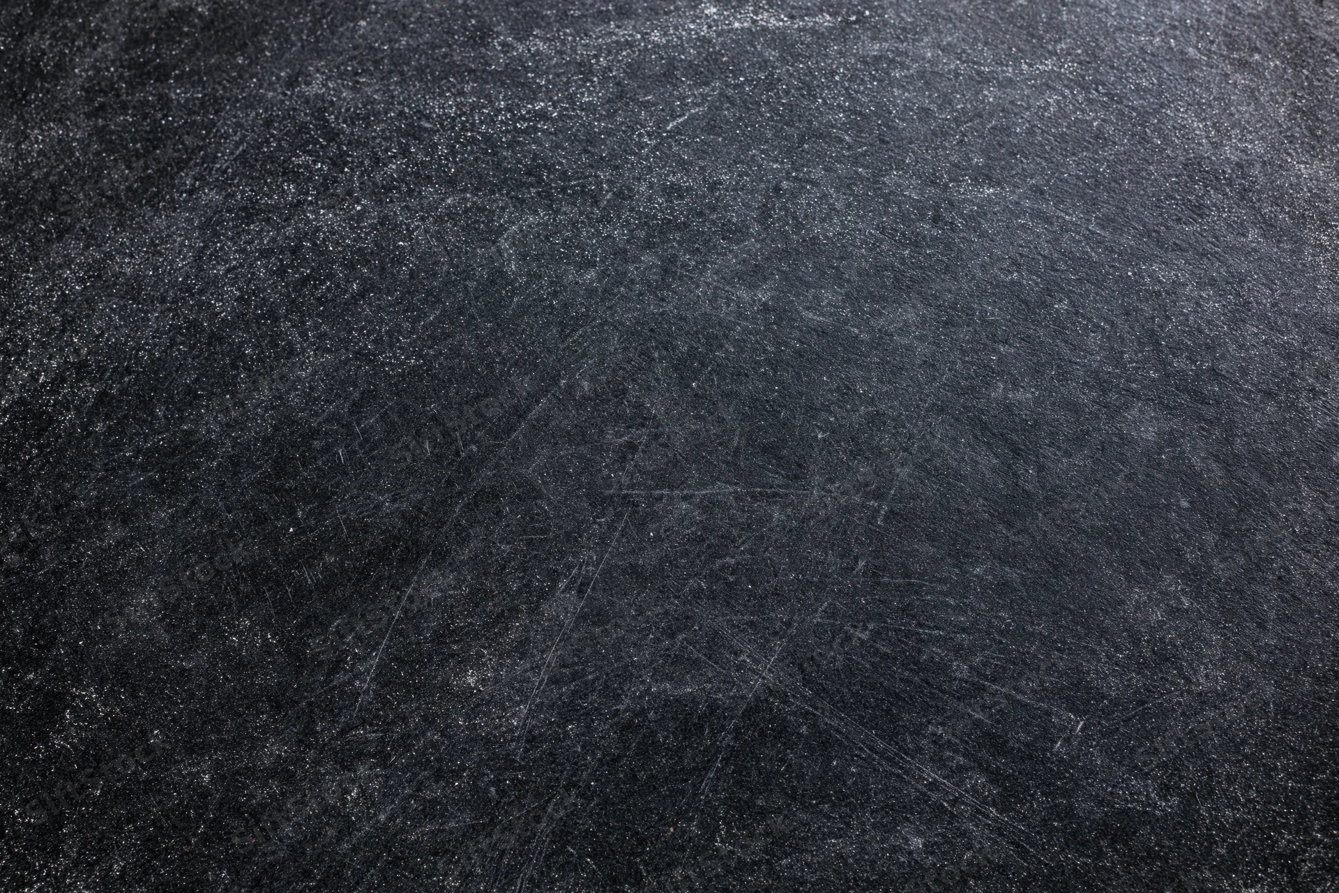 Close-up of a dark matte chalkboard surface with scratches and smudges showing texture and wear