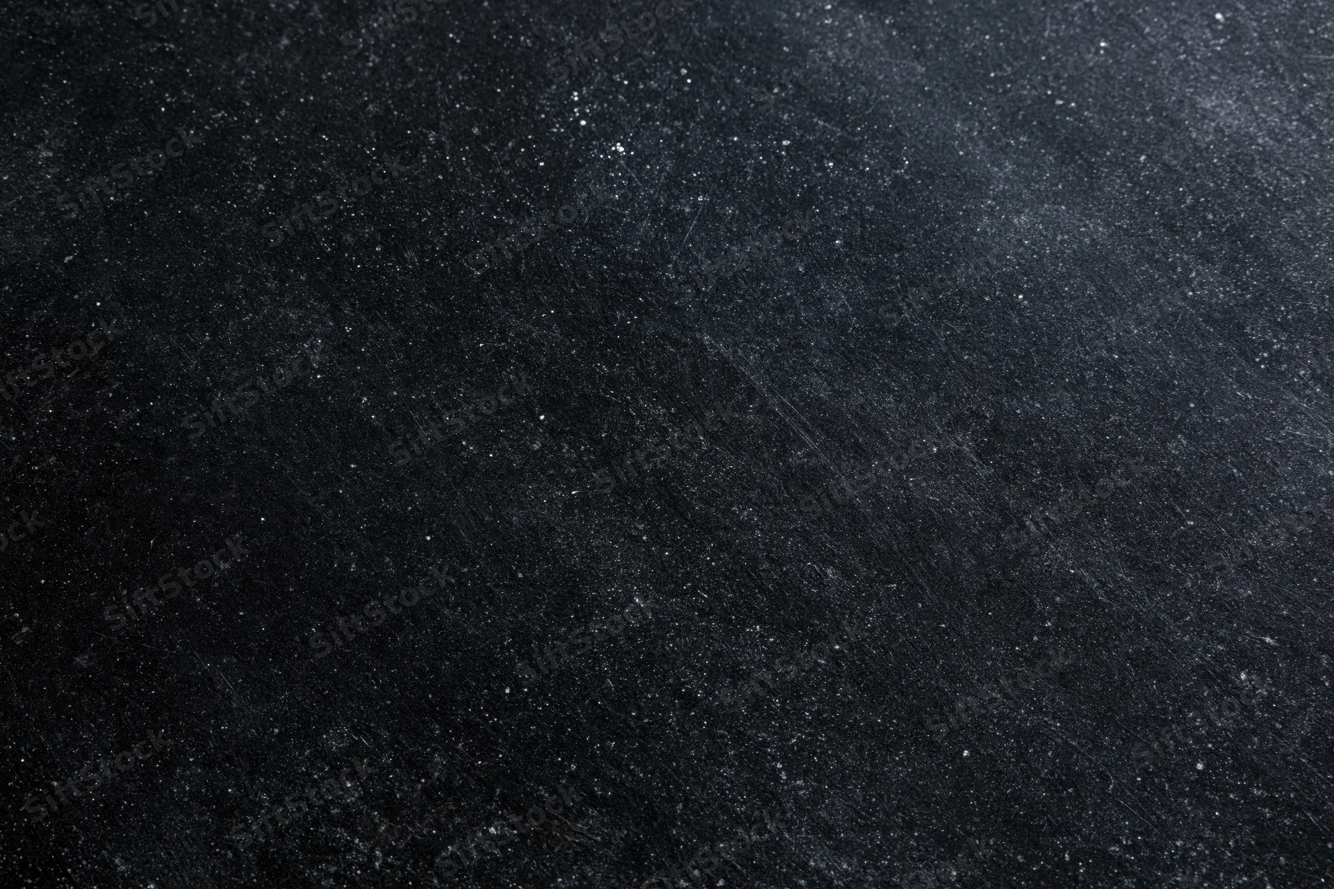 Close-up of a dark matte black chalkboard surface with fine texture and scattered white specks