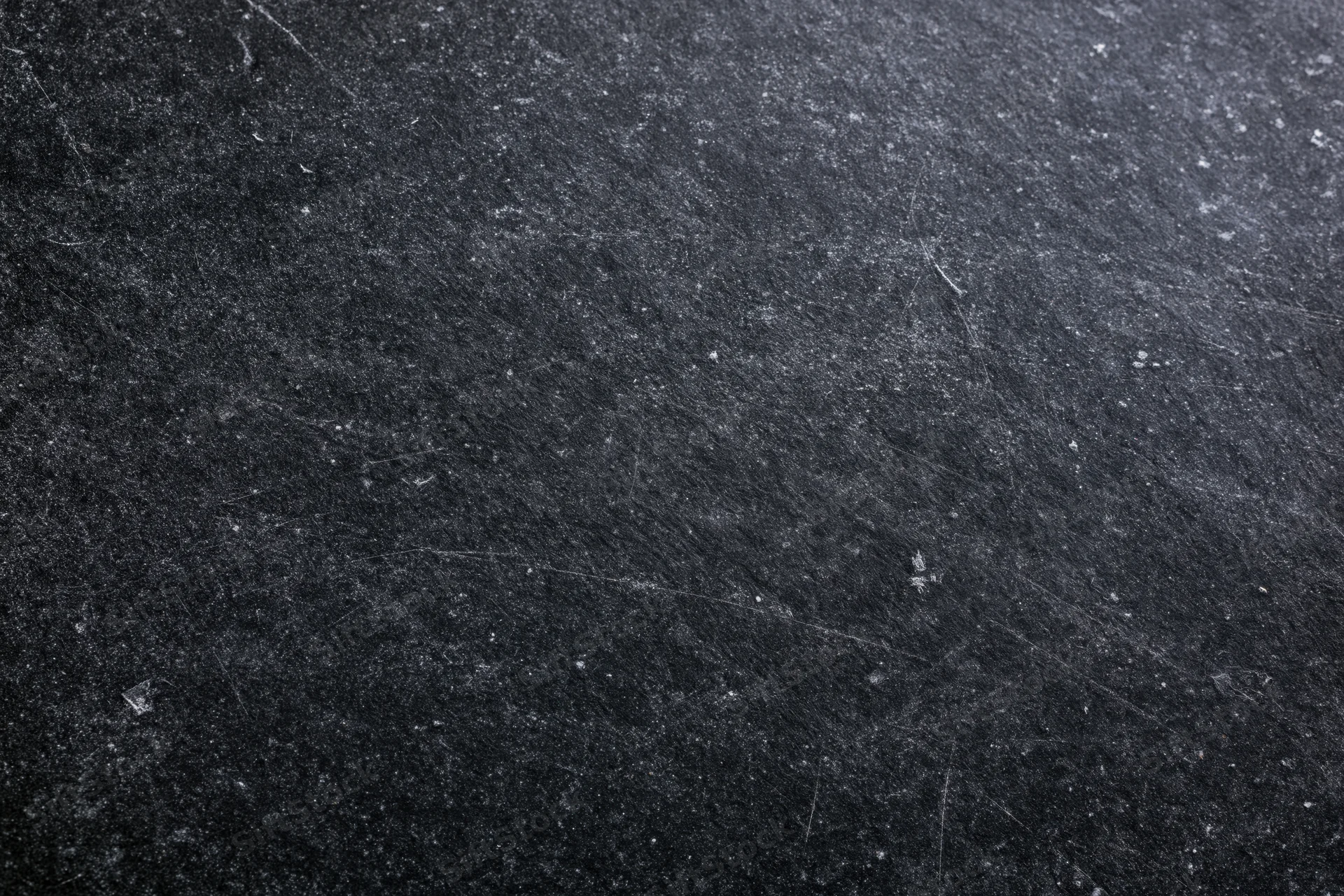 Close-up of a dark matte black chalkboard surface with scratches and texture