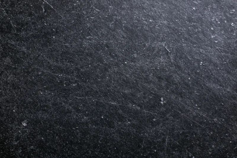 Close-up of a dark matte black chalkboard surface with scratches and texture
