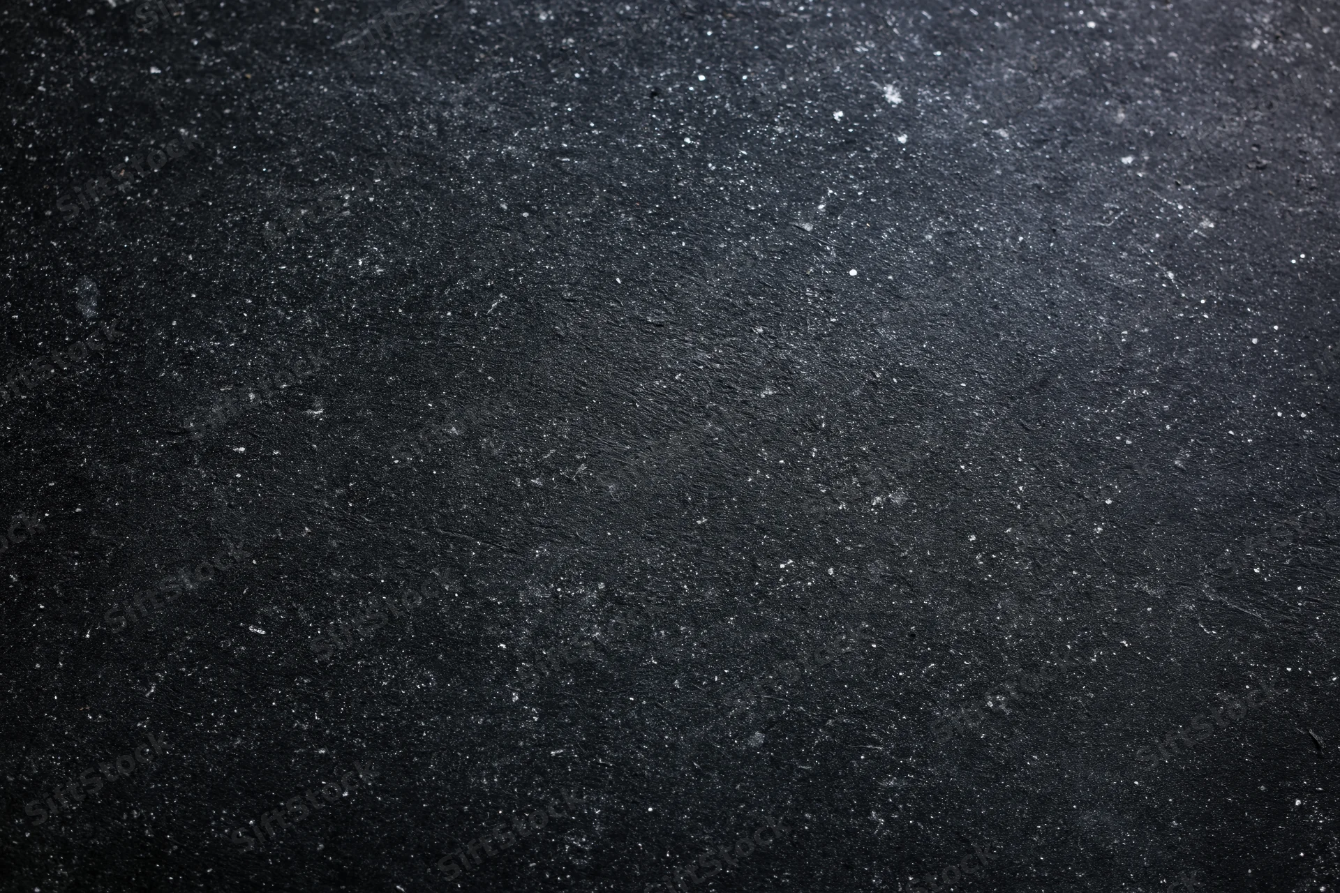 Close-up flat lay of a dark black chalkboard surface with speckled texture and matte finish