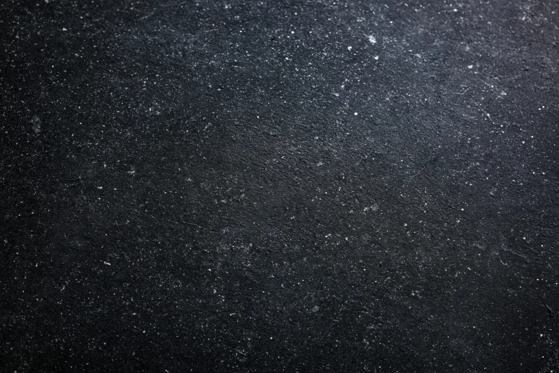 Close-up flat lay of a dark black chalkboard surface with speckled texture and matte finish
