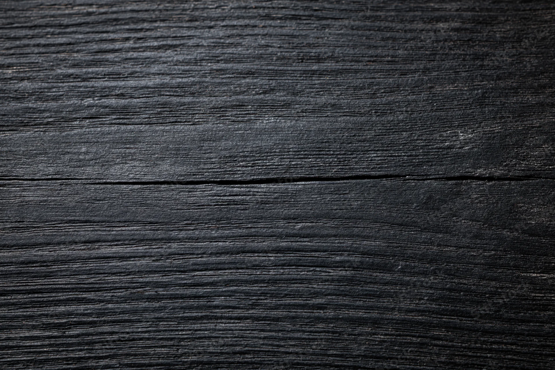 Close-up of dark black wooden surface with visible grain and texture