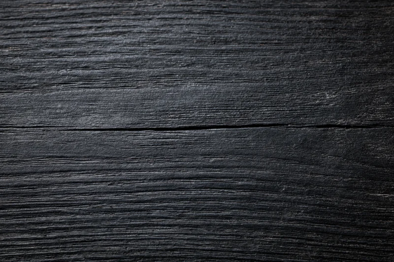 Close-up of dark black wooden surface with visible grain and texture
