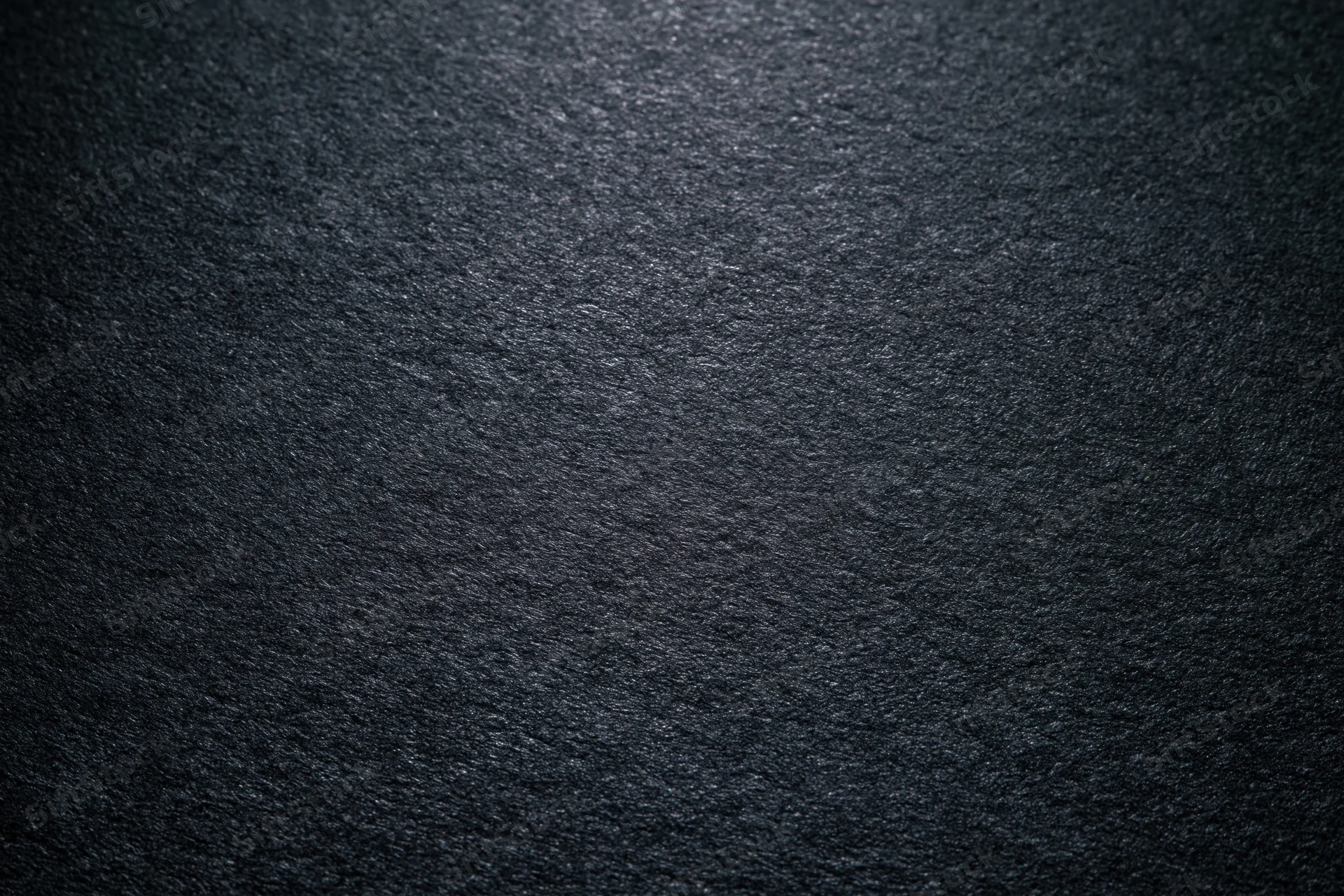 Close-up of dark charcoal matte paper surface with textured grain and soft lighting gradient