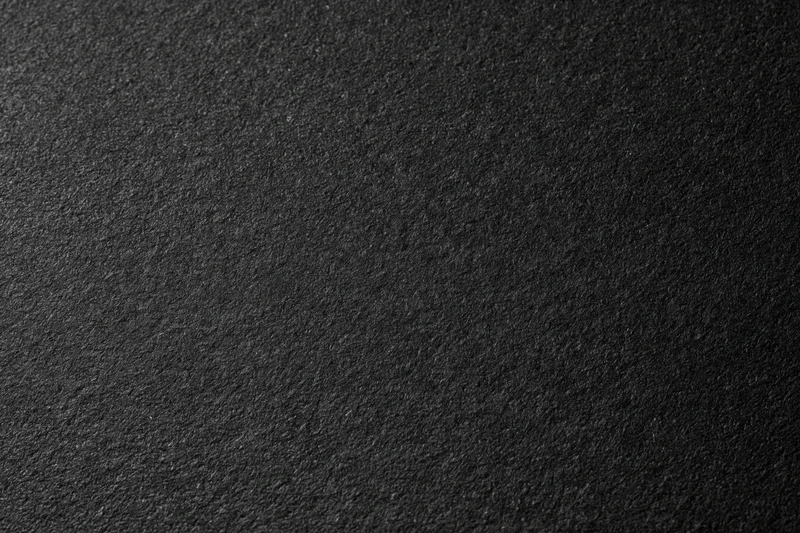 Close-up of dark charcoal matte paper surface with fine grain texture