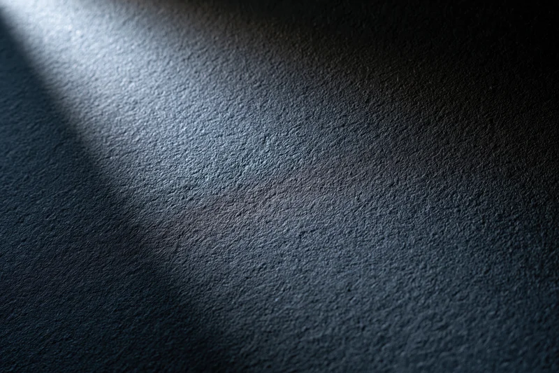 Close-up of a dark matte textured surface with light and shadow gradient