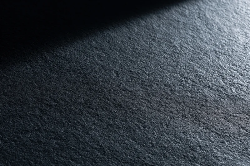 Close-up of dark matte textured surface with light and shadow gradient