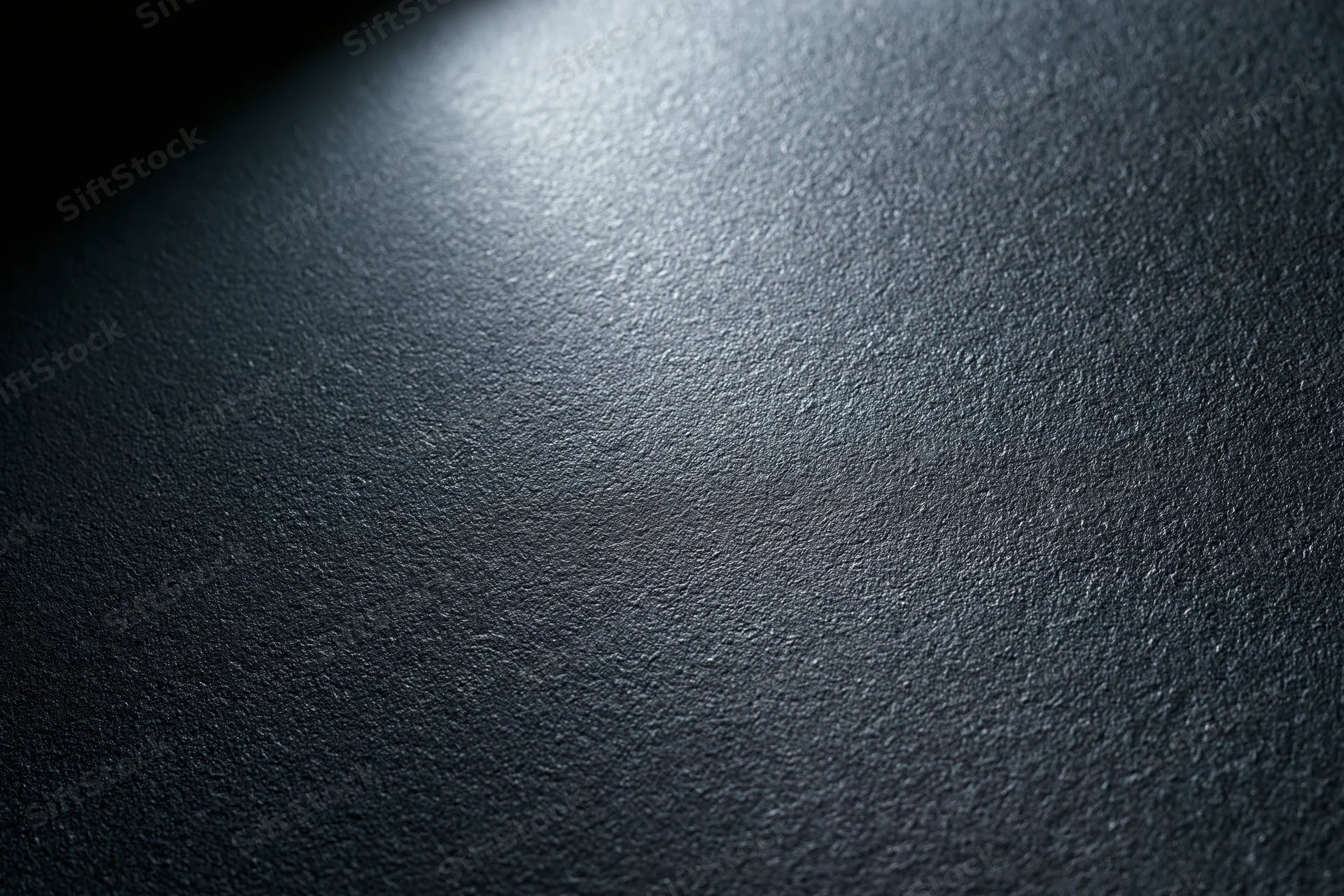 Close-up of a dark matte textured surface with soft lighting gradient