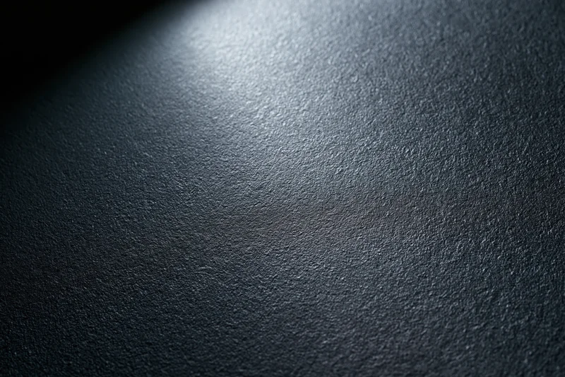 Close-up of a dark matte textured surface with soft lighting gradient