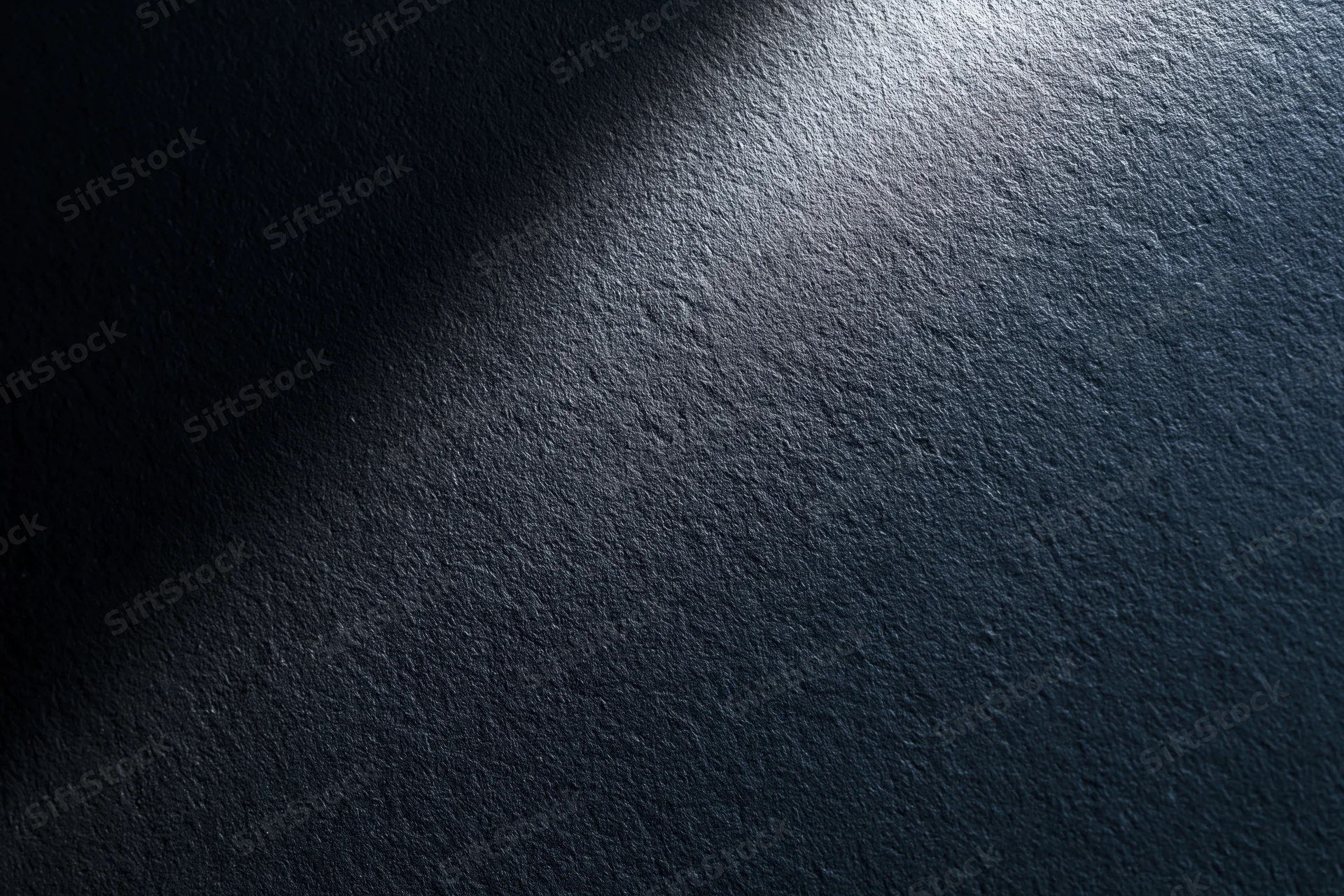 Dark matte textured surface with spotlight gradient and shadowed edges