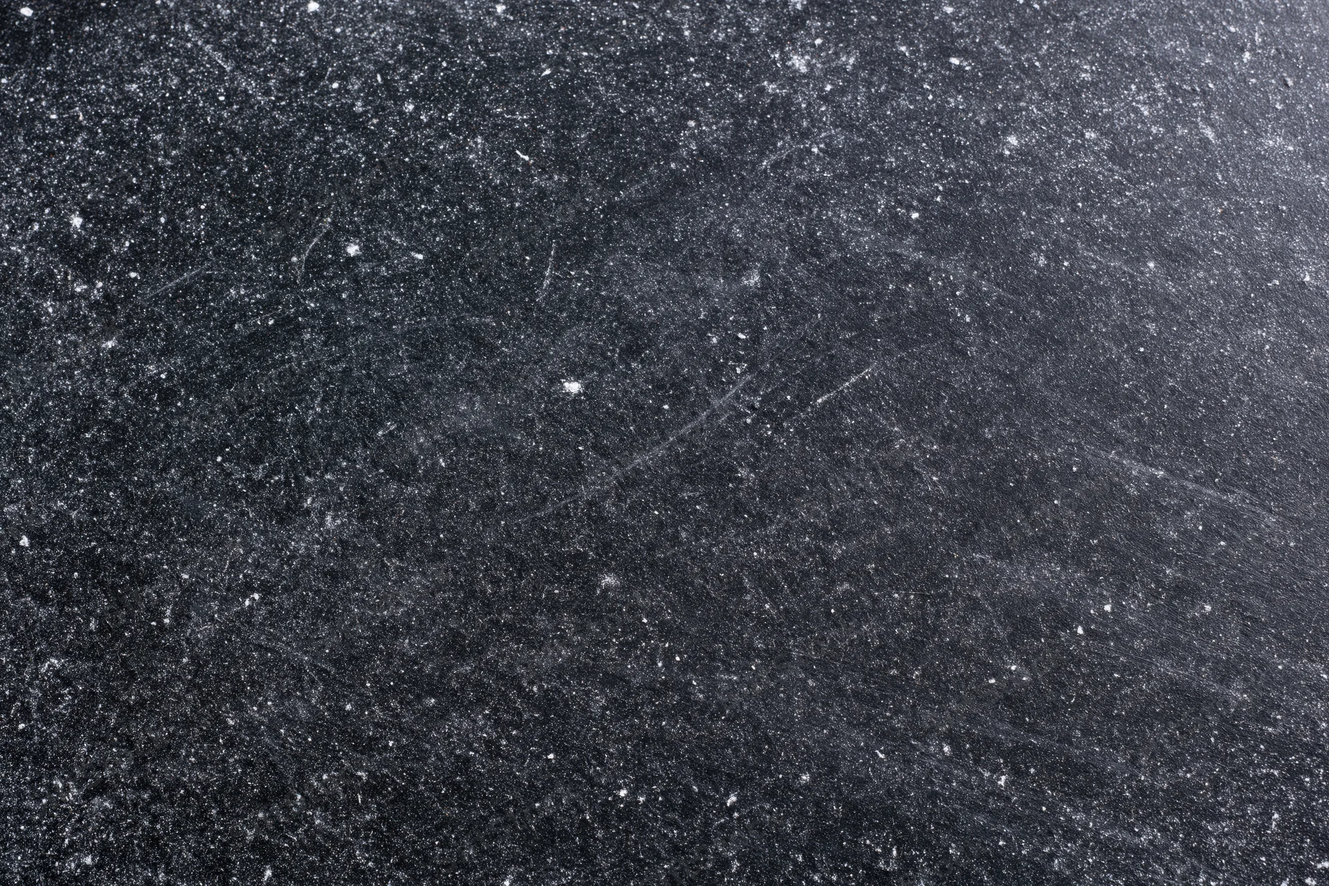 Close-up of a dark scratched chalkboard surface with white specks and marks