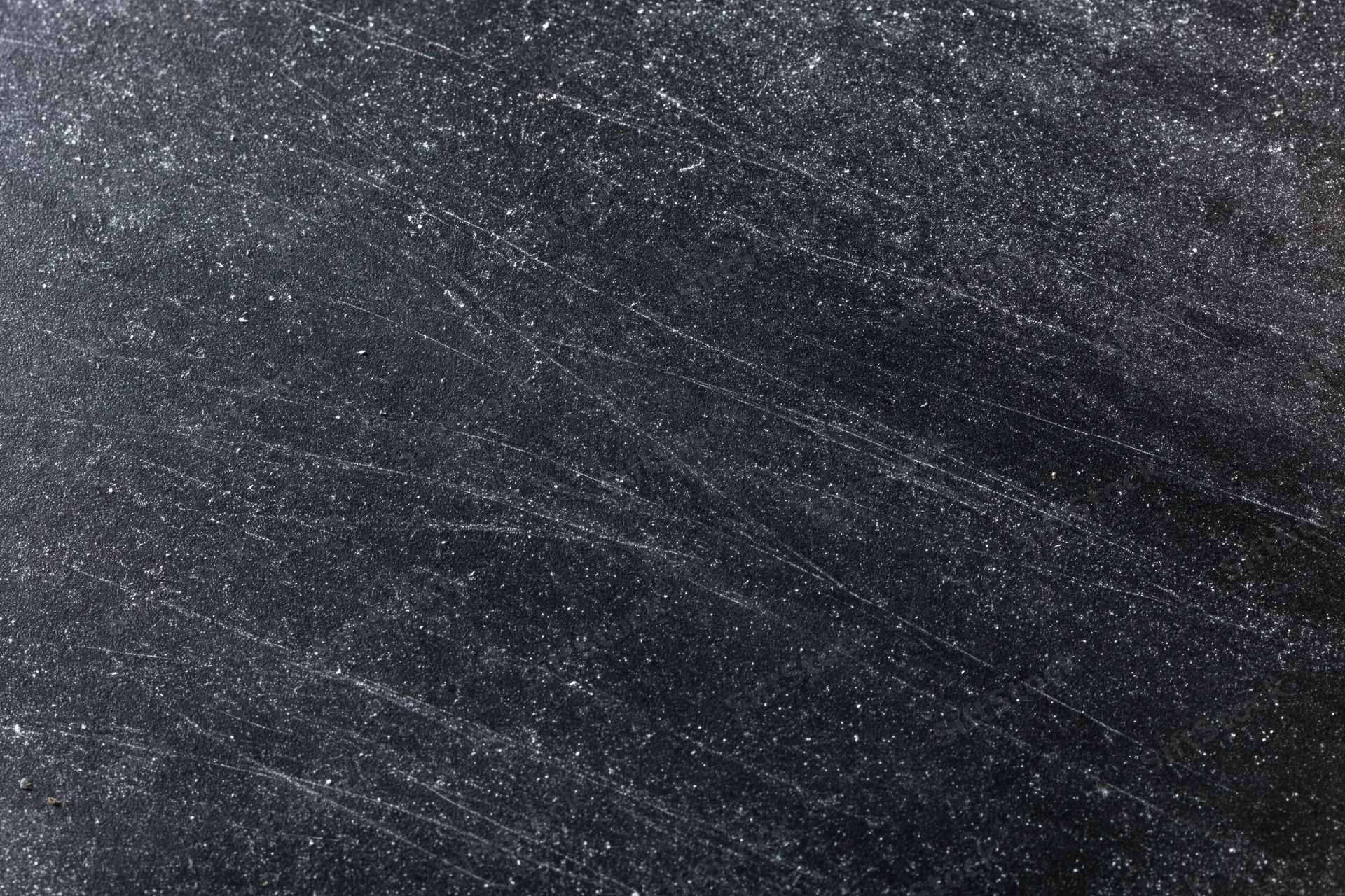 Close-up of a dark scratched chalkboard surface with white residue and scuff marks