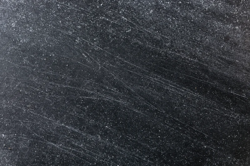 Close-up of a dark scratched chalkboard surface with white residue and scuff marks