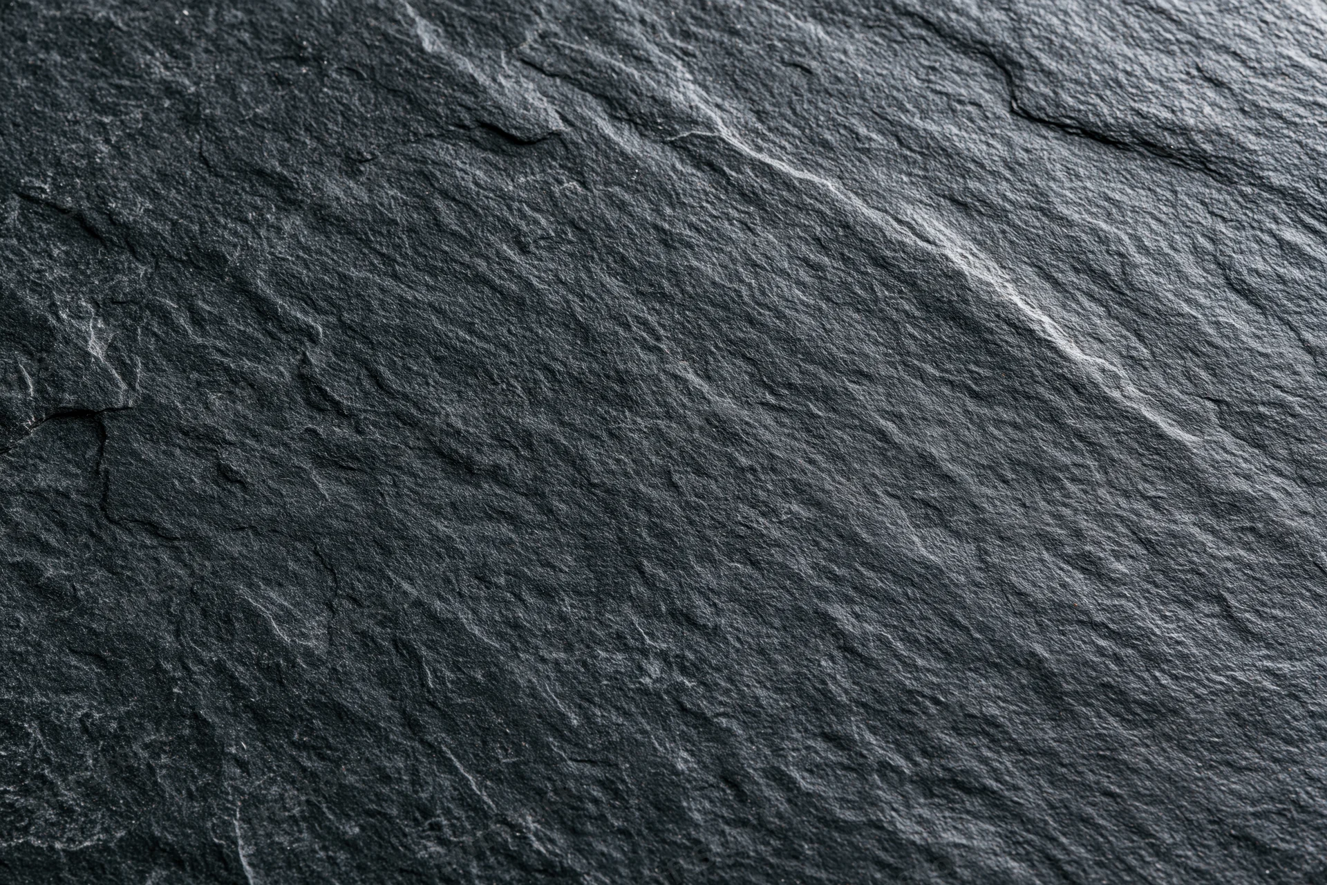 Close-up of dark slate stone surface with natural cracks and texture